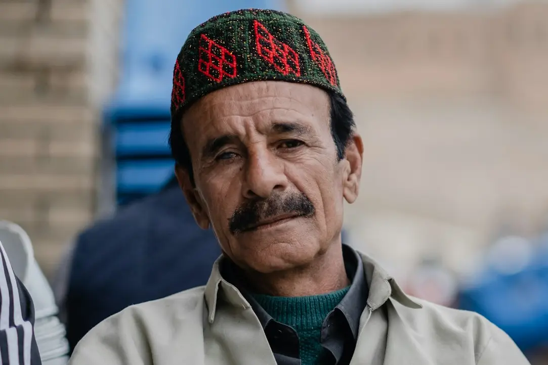 man in gray button up shirt wearing blue and red knit cap